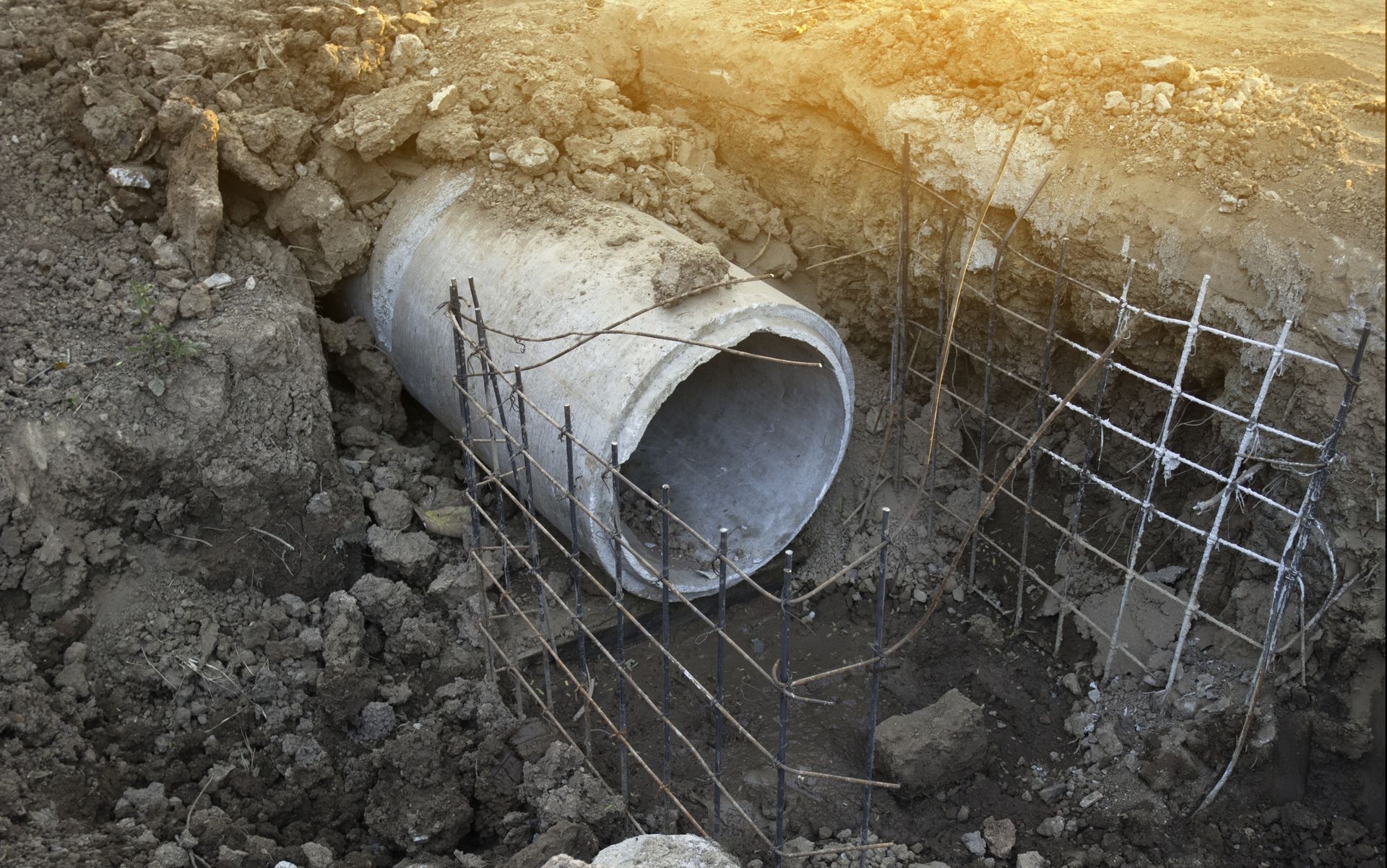 A large concrete pipe is sitting in the dirt.