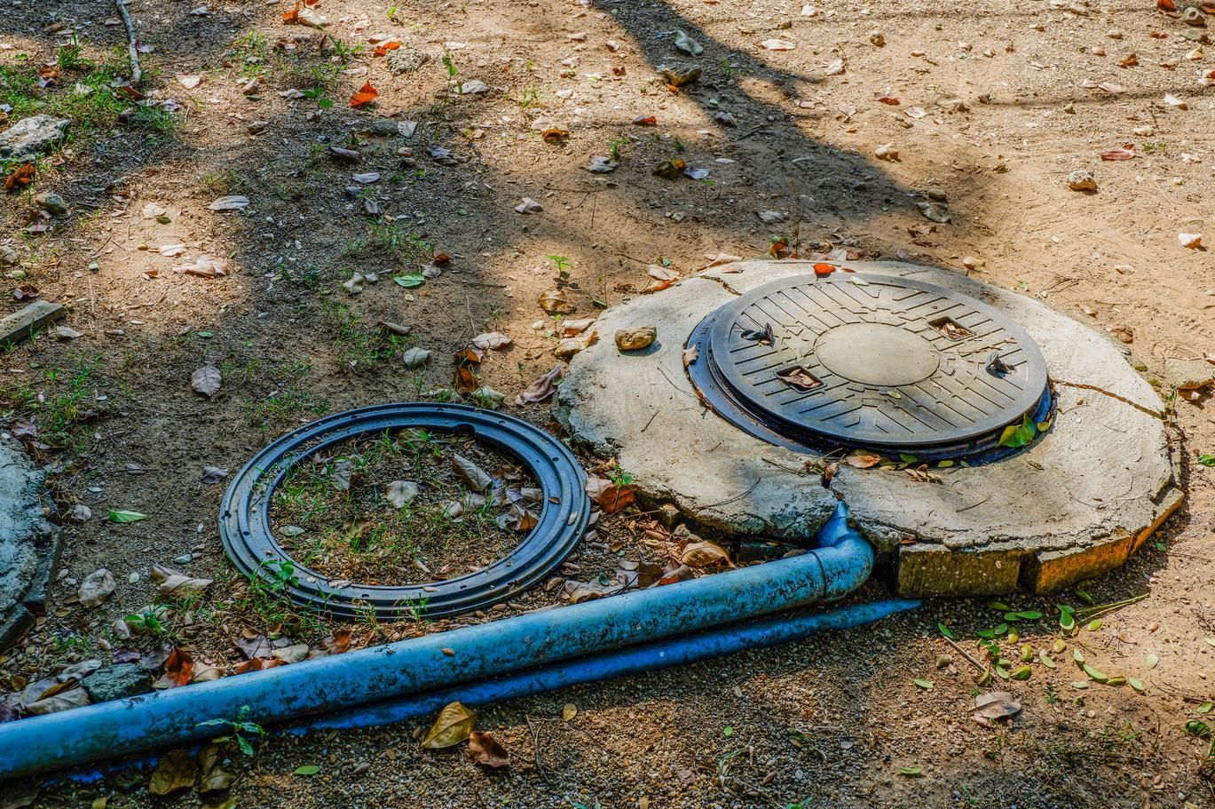 A manhole cover is sitting on the ground next to a pipe.