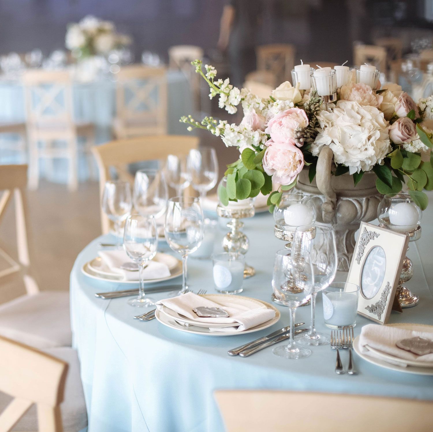 Wedding reception table set with flowers, glassware, and blue tablecloth.