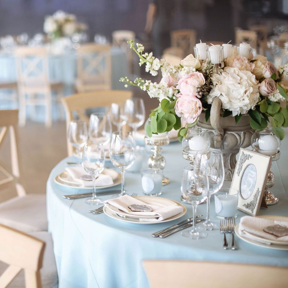 Wedding reception table set with flowers, glassware, and blue tablecloth.