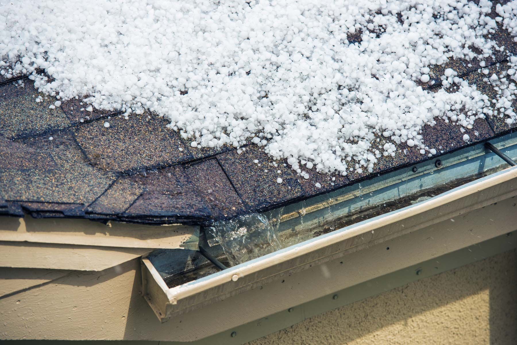 hail sitting on roof with water flowing. hail damage to roof