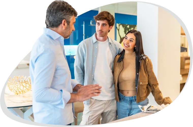 Three people in a bright office, chatting with a man in a light blue shirt