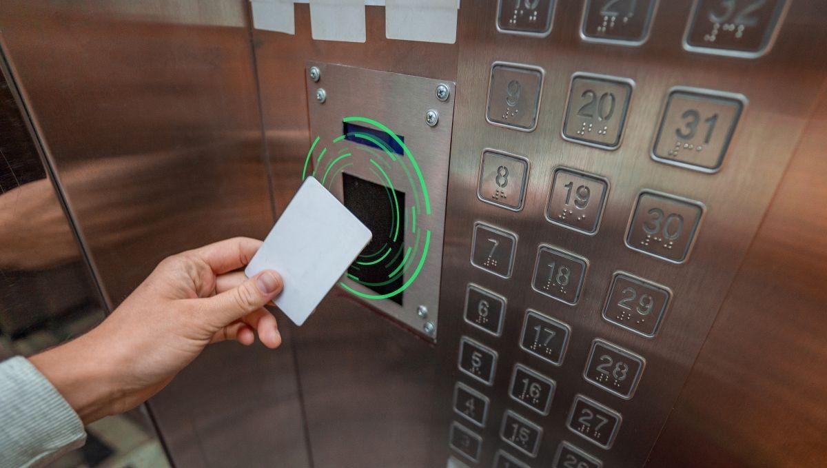 card reader access: hand holding a white card near an elevator control panel with floor buttons