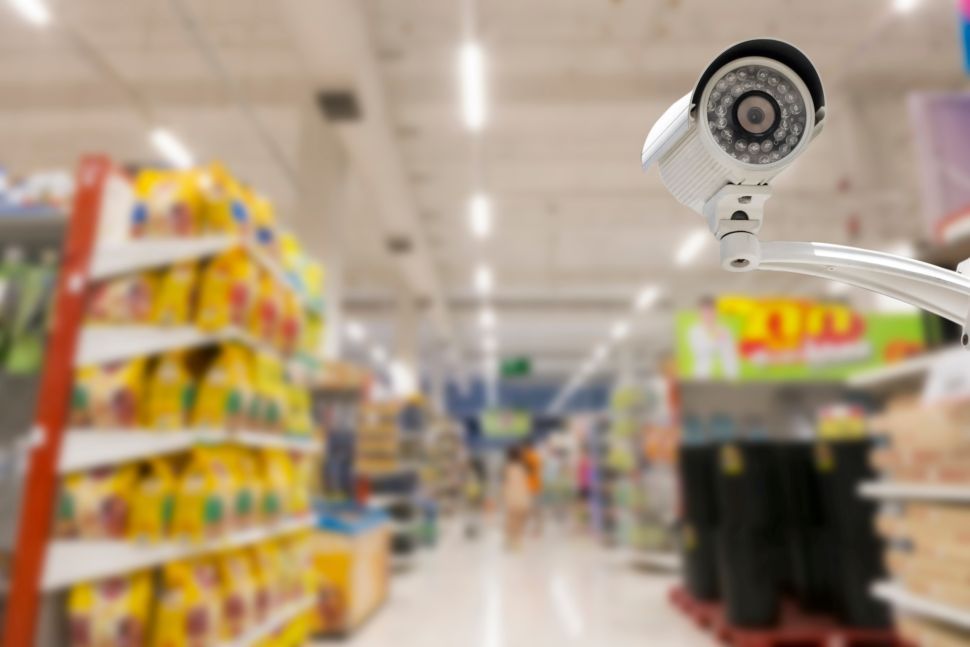 Security camera in a store aisle, focused on products and shoppers.