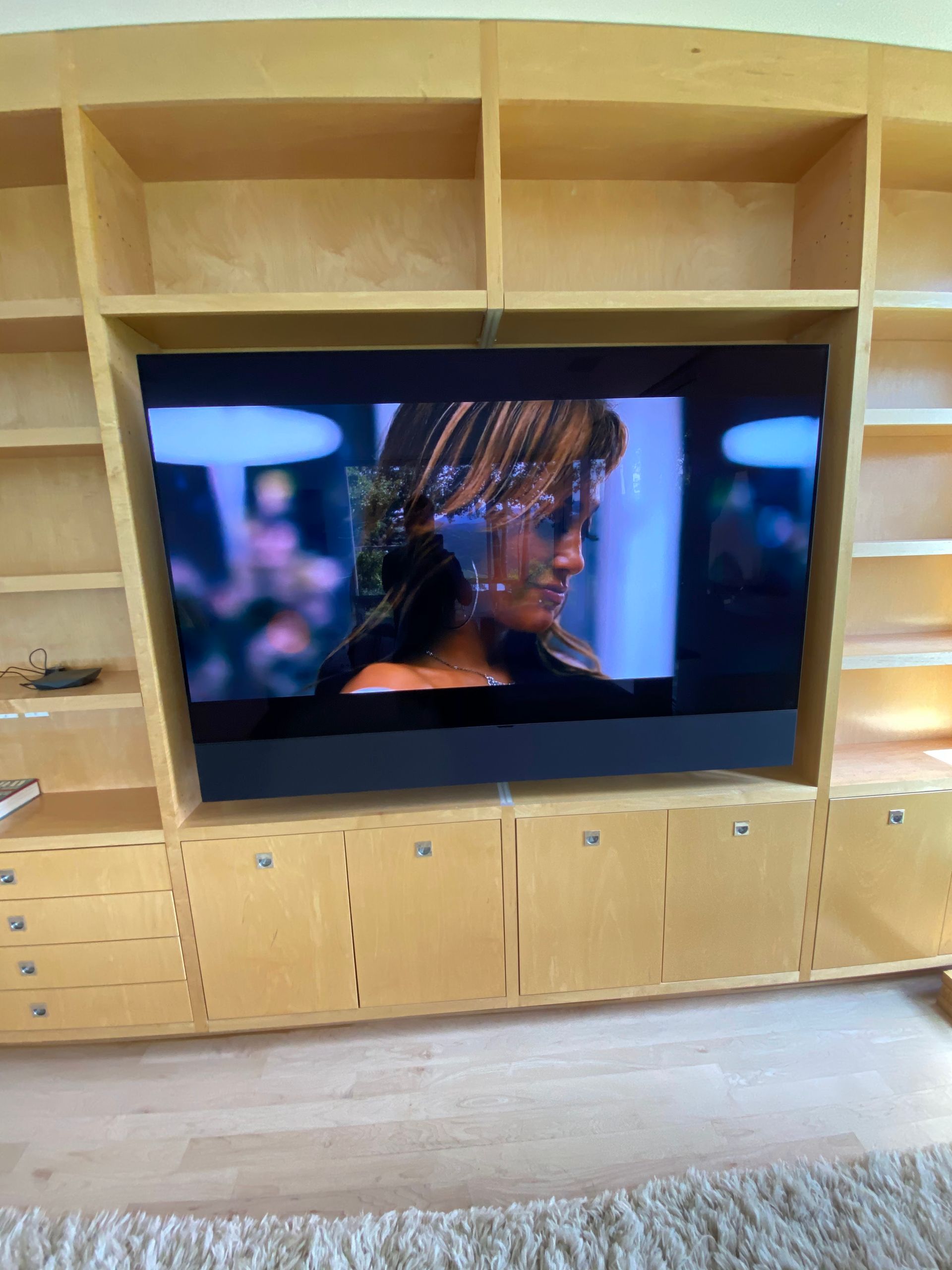 A large flat screen tv is sitting on top of a wooden entertainment center.