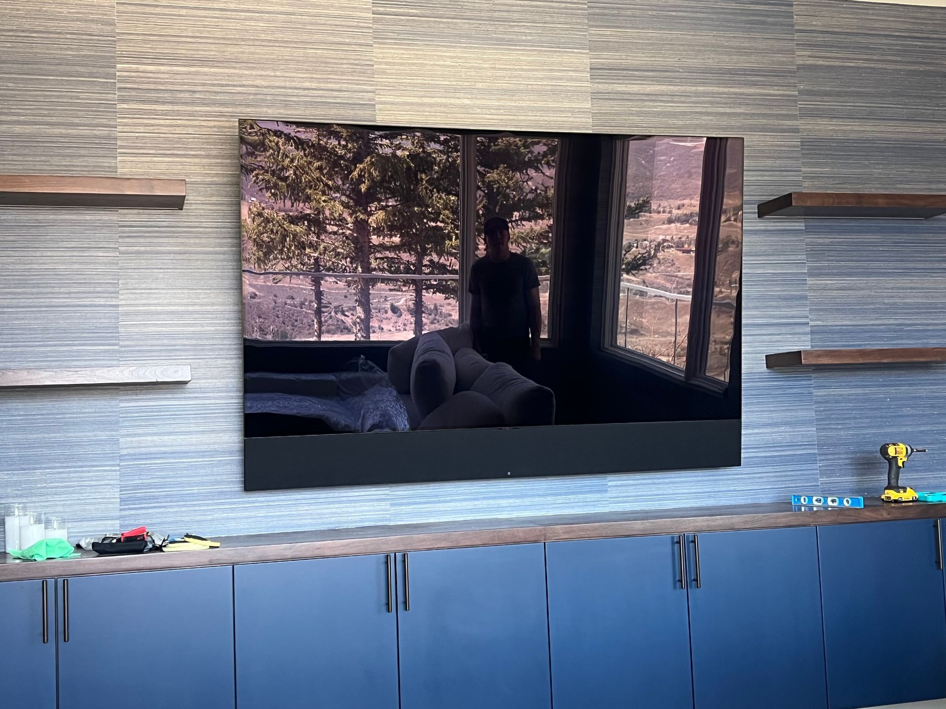 A large flat screen tv is mounted on a wall above a kitchen counter.