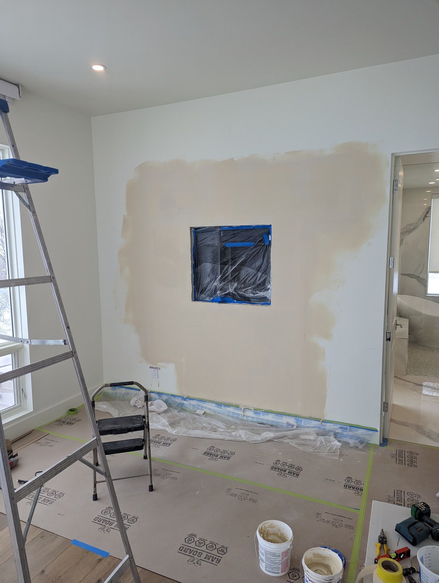 A room is being painted with a ladder and buckets of paint.