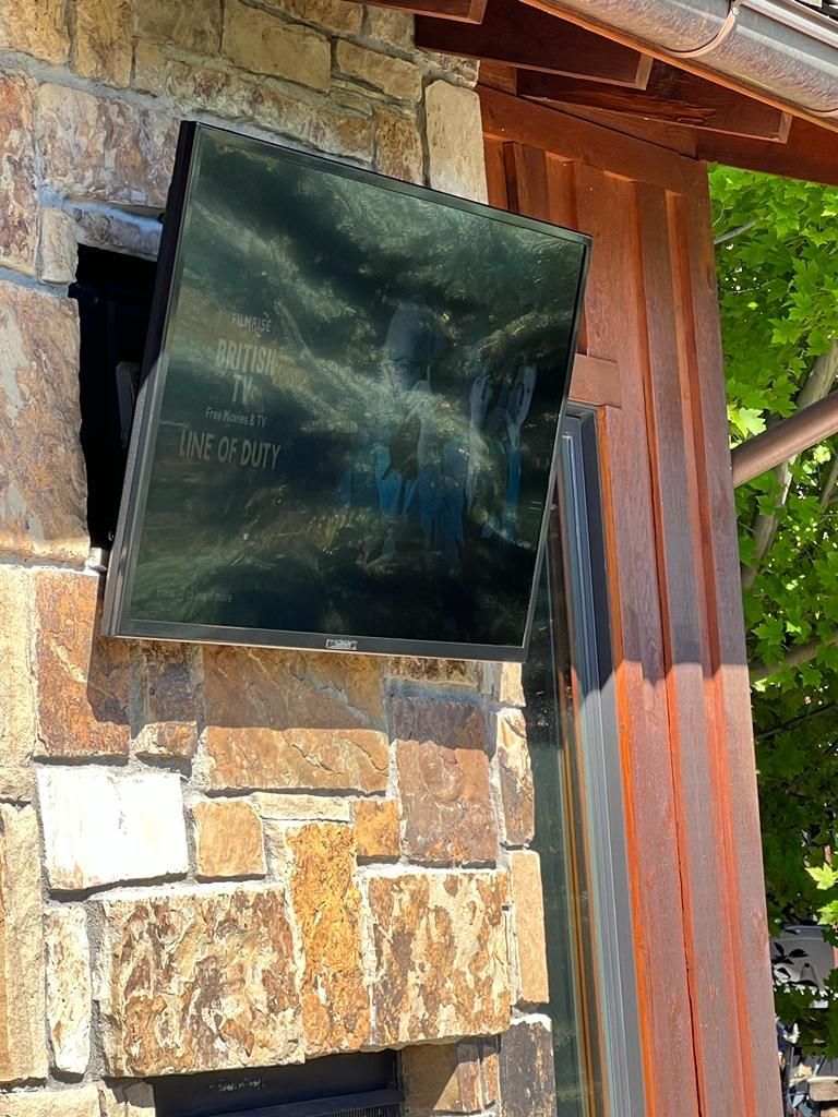 A tv is mounted on the side of a stone wall.