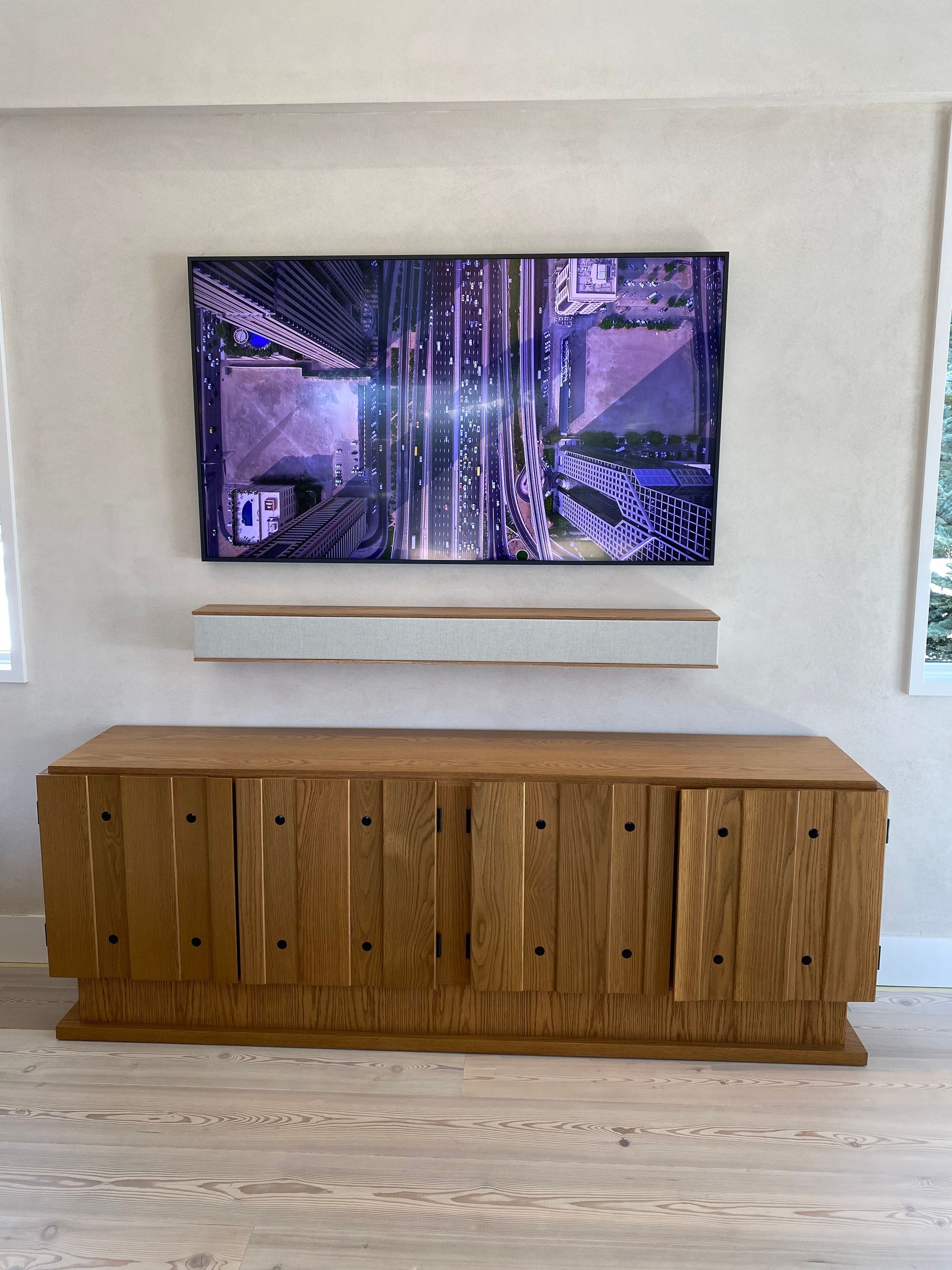 A large flat screen tv is hanging on a wall above a wooden entertainment center.