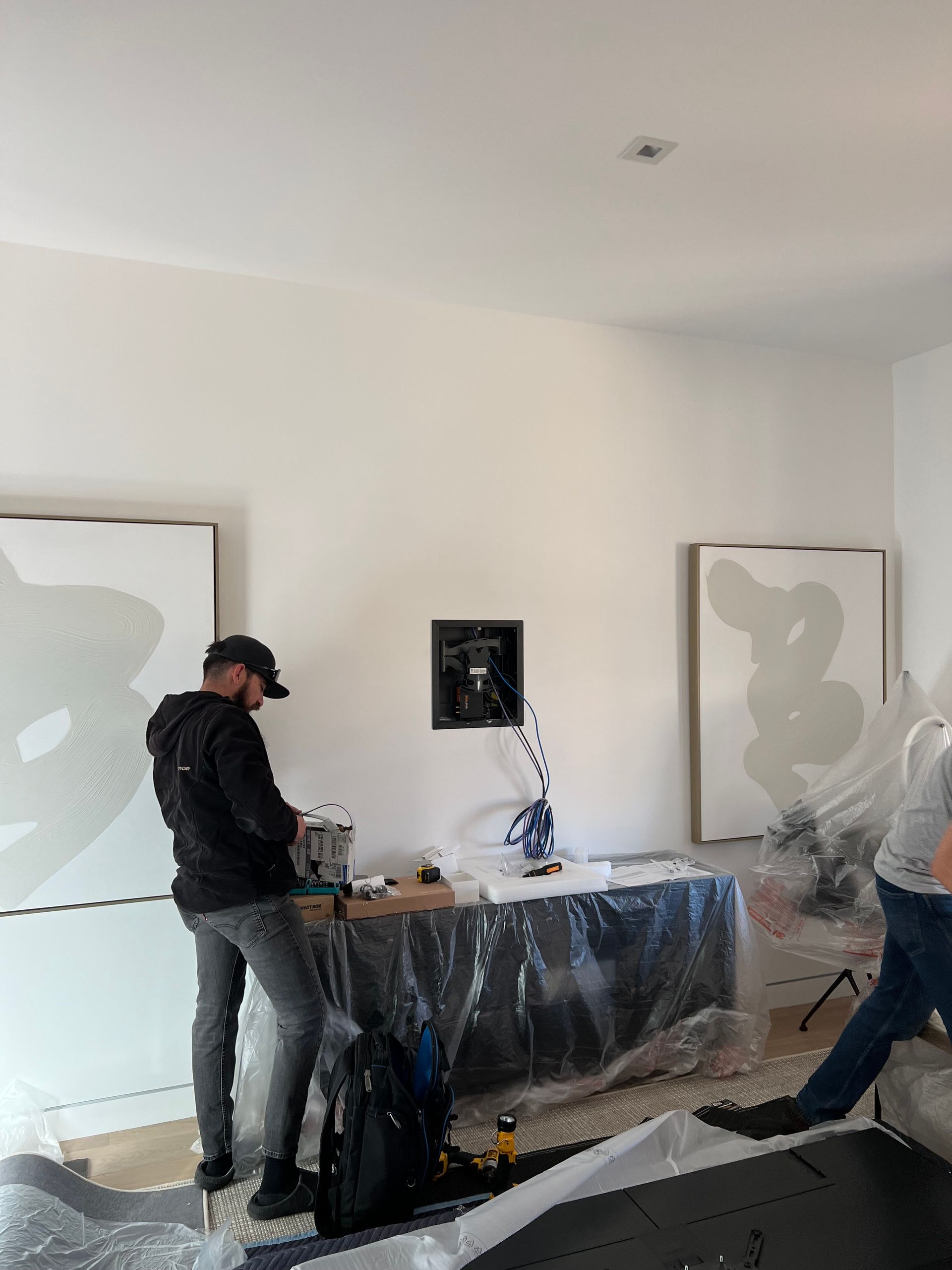 A man is standing in a room with paintings on the wall.