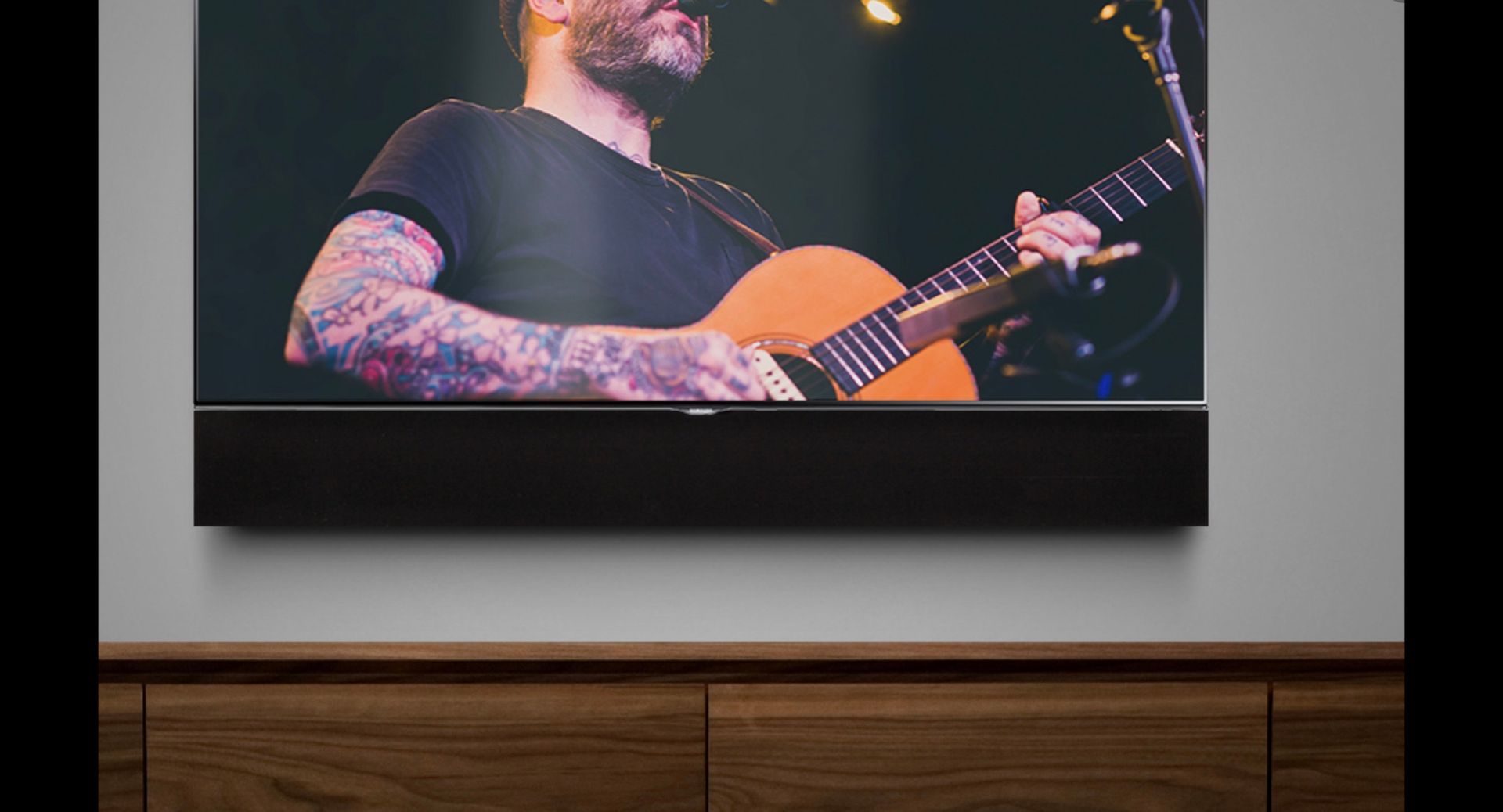 A man is playing a guitar on a television screen.