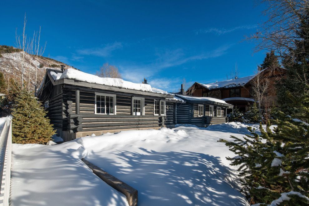 A log cabin is sitting in the middle of a snow covered field.