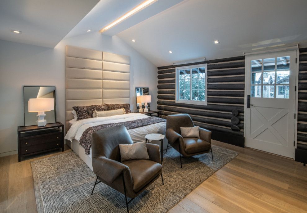 A bedroom in a log cabin with a bed , chairs , and a window.