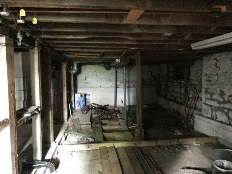An empty basement with wooden beams and a concrete wall.
