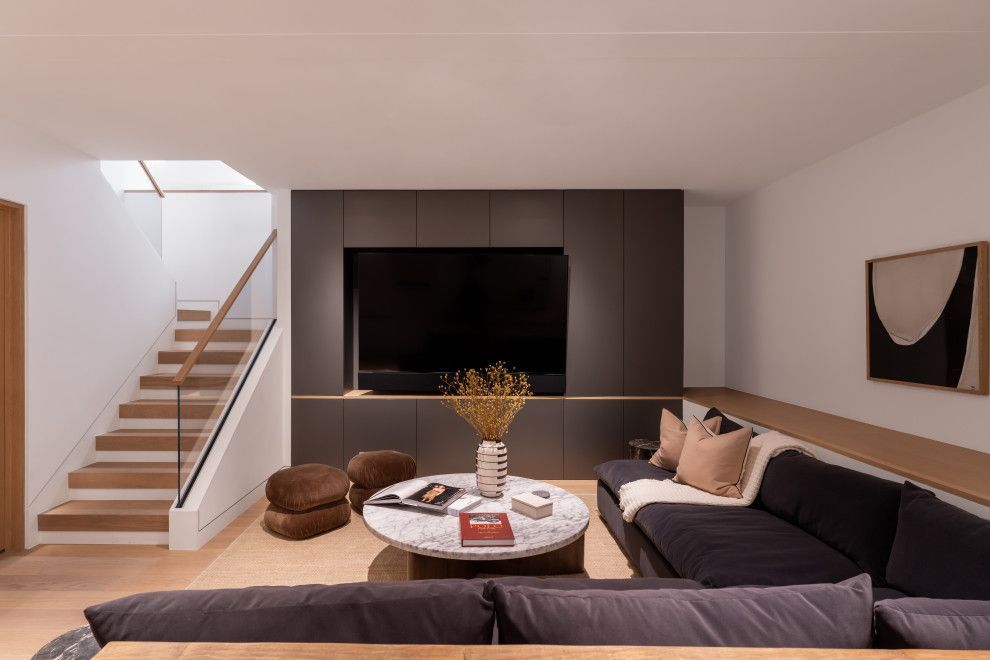 A living room with a couch , table , television and stairs.