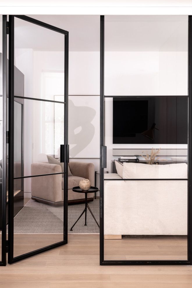 A living room with a couch and a television behind glass doors.
