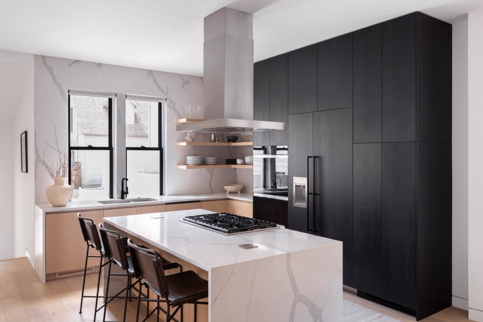 A kitchen with black cabinets and a large island in the middle.