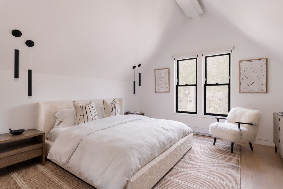 A bedroom with a bed , chair , nightstand and two windows.