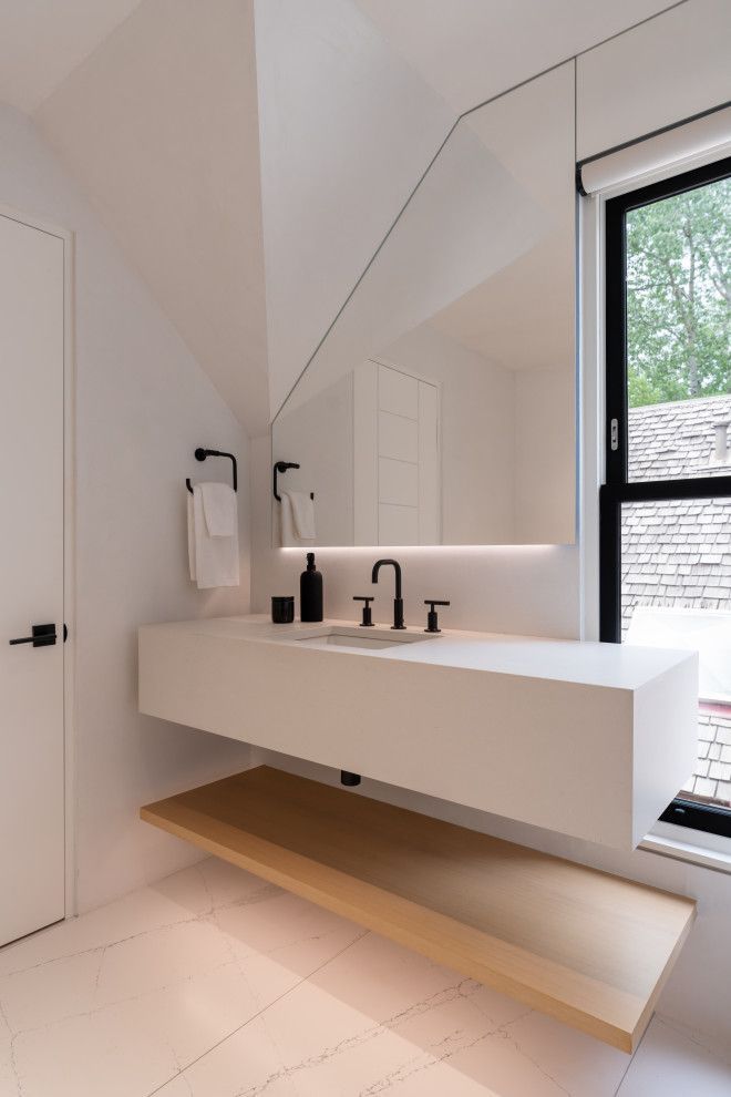 A bathroom with a sink , mirror and window.