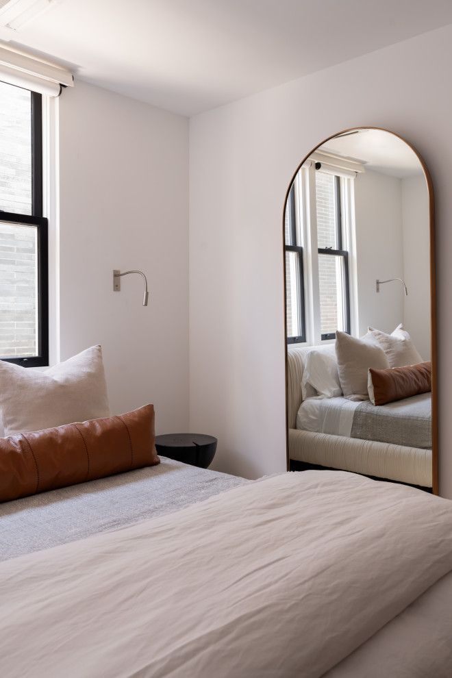 A bedroom with a bed and a large mirror on the wall.
