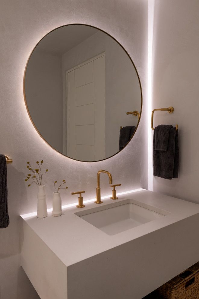 A bathroom with a sink and a round mirror.