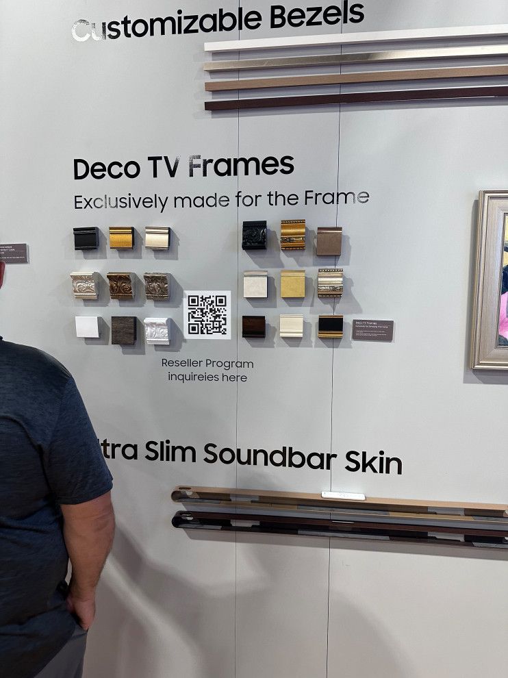 A man is standing in front of a wall with deco tv frames on it.