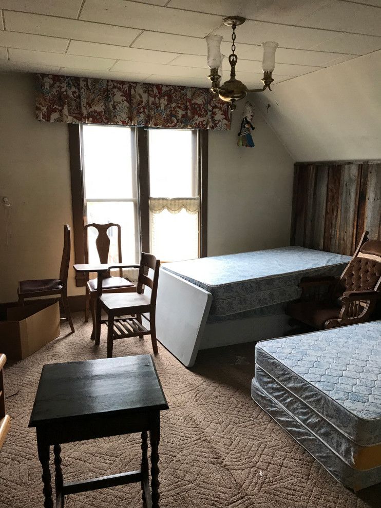 A bedroom with two beds , a table , chairs and a chandelier.