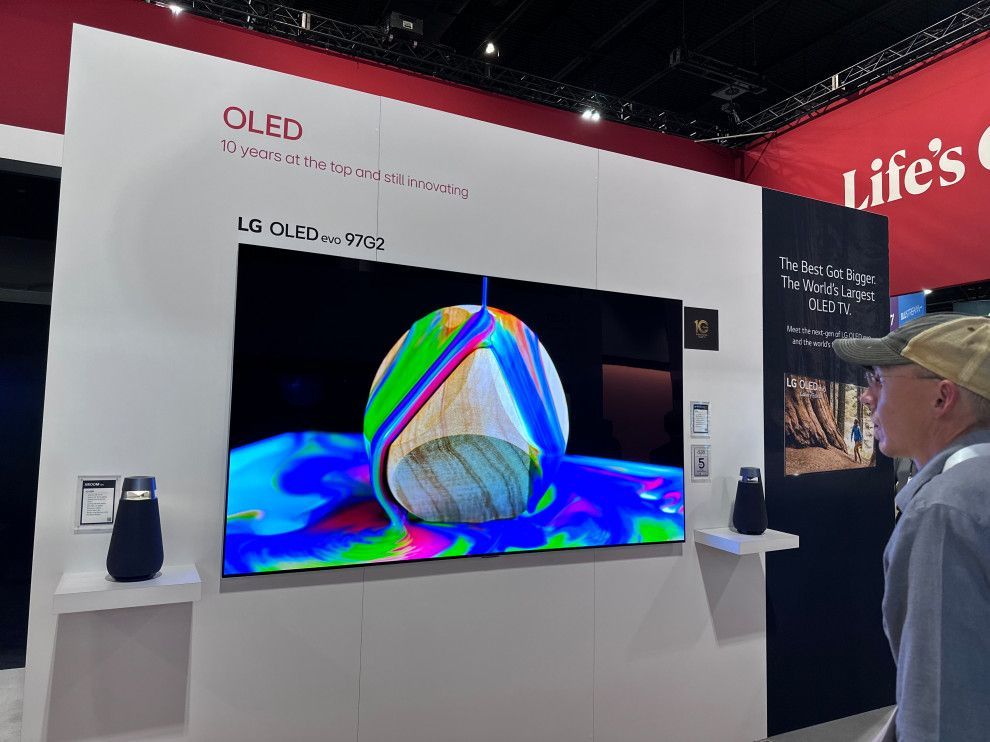 A man is looking at an lg oled tv on a wall.