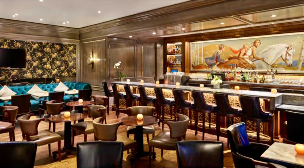 A restaurant with tables and chairs and a long bar.