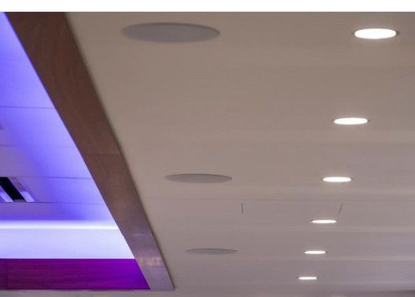 A ceiling with purple and white lights and speakers