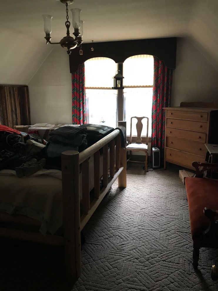 A bedroom with a bed , dresser , chair and window.