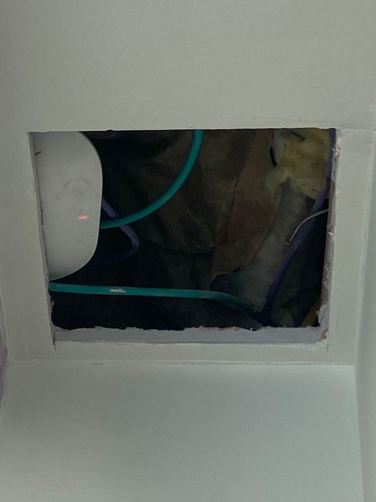 A picture of a hole in the wall with wires coming out of it.