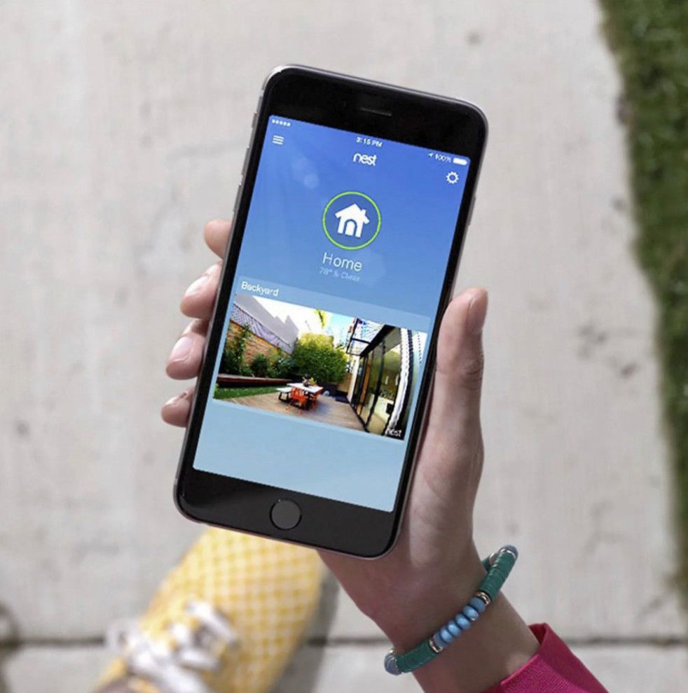 A person is holding a smart phone with a picture of a house on the screen.