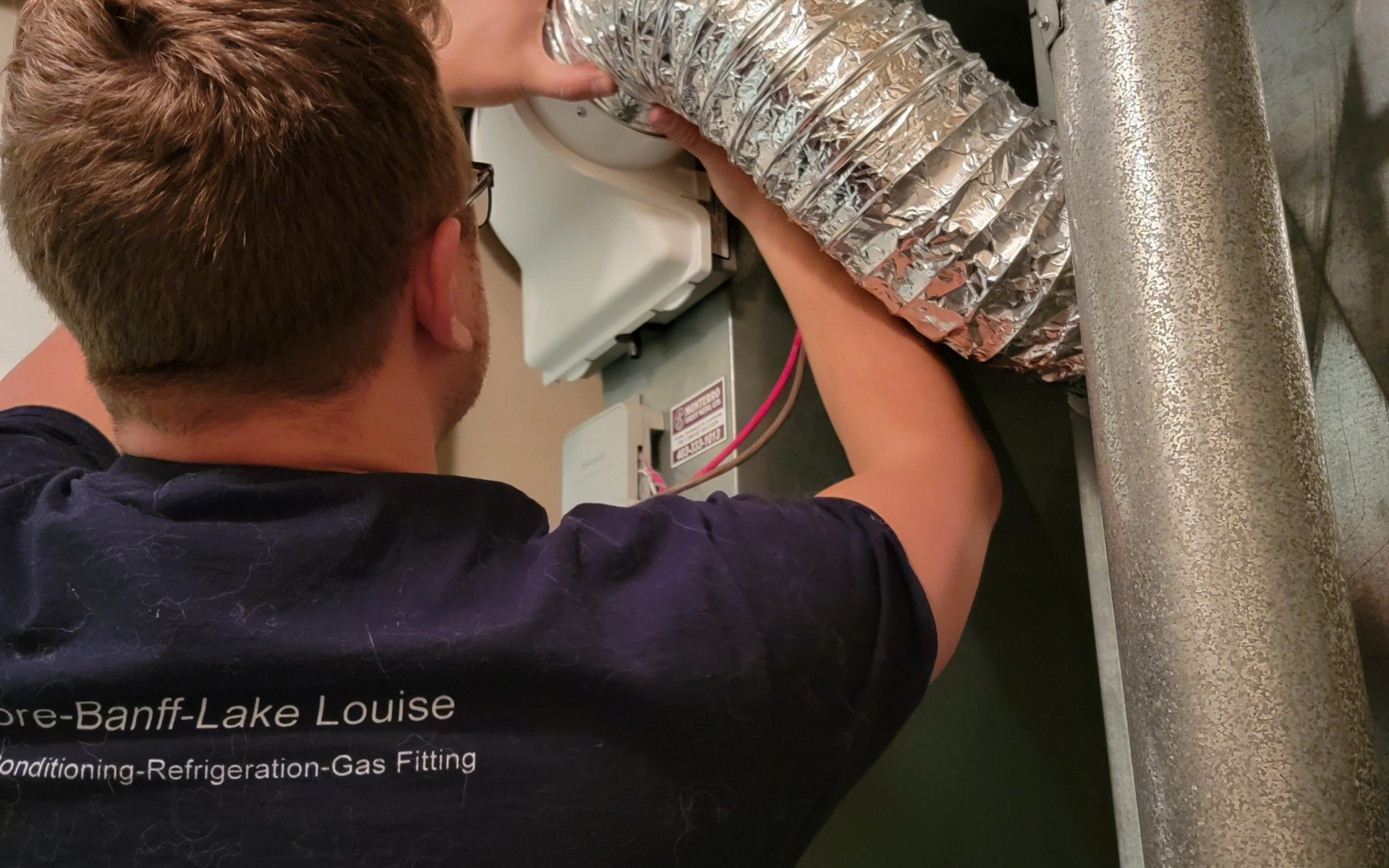 Person connecting flexible ductwork to an HVAC unit.