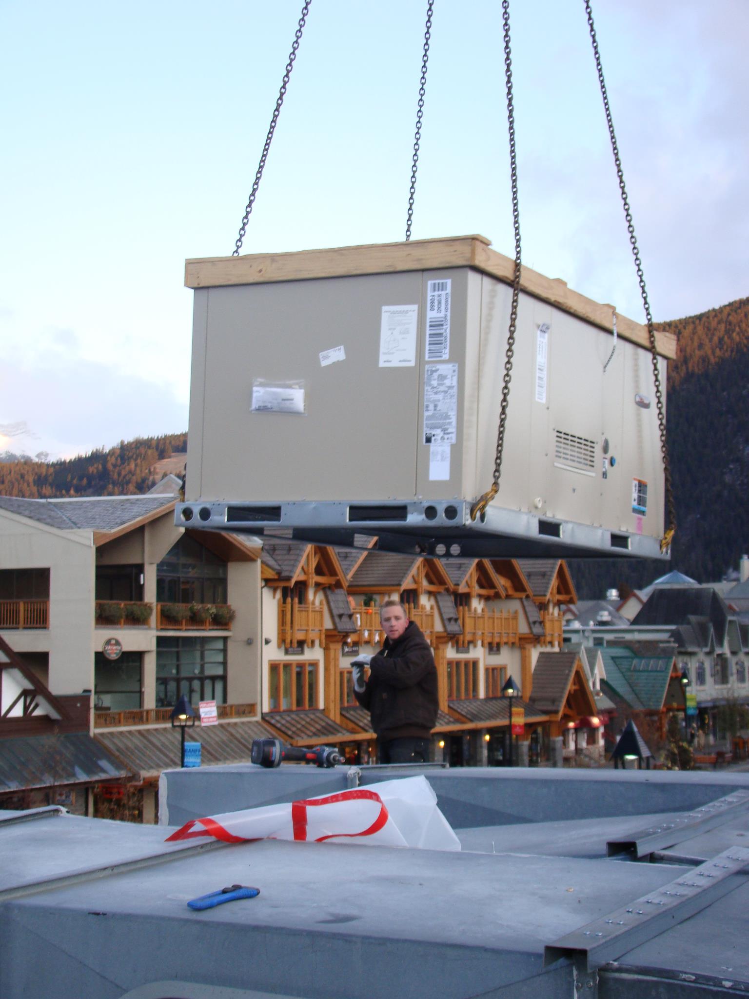 A large box is being lifted by a crane in a small town