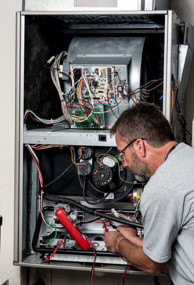 HVAC technician working on furnace, using a multimeter; indoor setting.