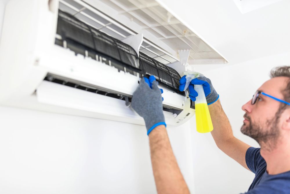 A man is cleaning an air conditioning unit.