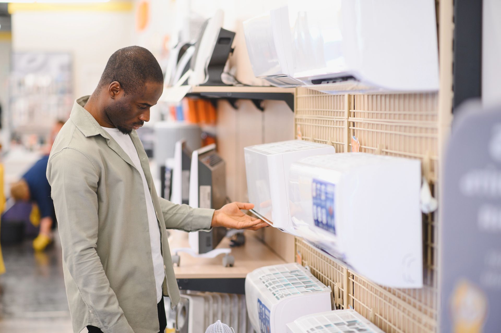Man examining an air conditioner at an appliance store.