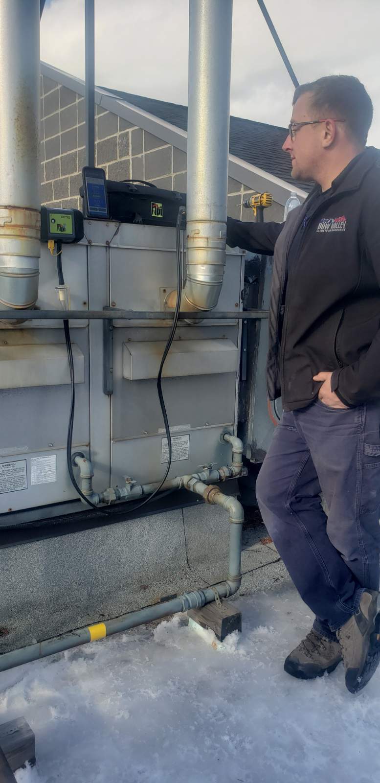 A man is standing next to a machine in the snow.
