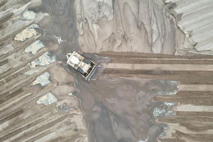 An aerial view of a bulldozer driving through a dirt field.