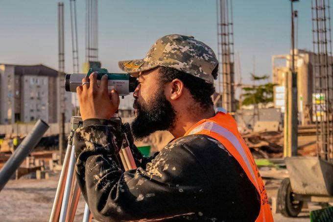 A man is looking through binoculars at a construction site.