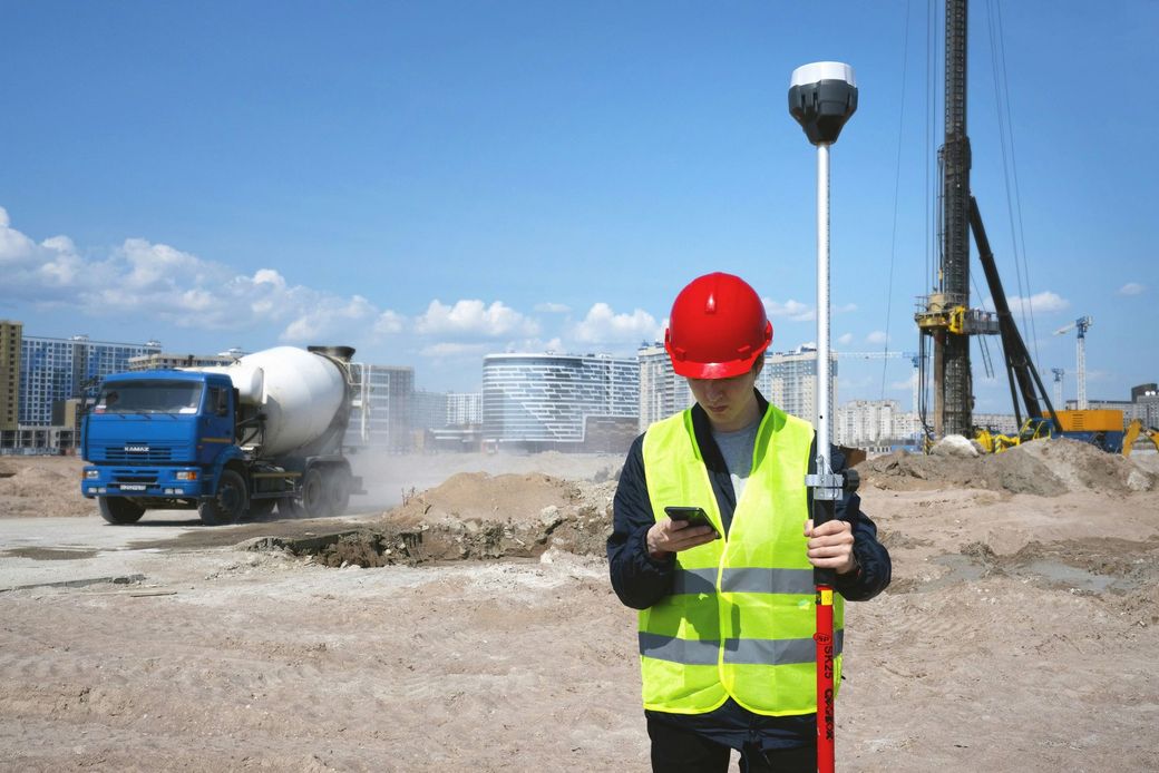 A construction worker is using a cell phone at a construction site.