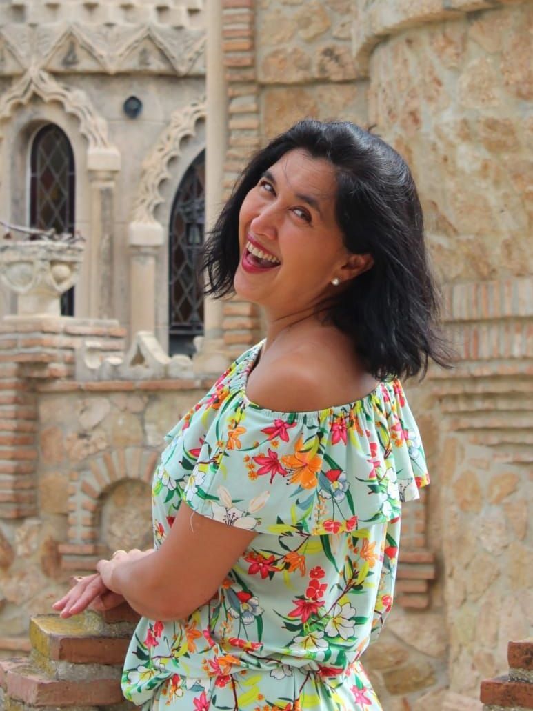 Kanke con un vestido floral está parada frente a un castillo.