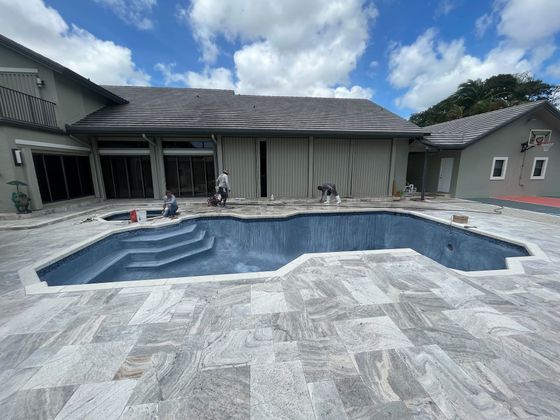 A large swimming pool is being built in the backyard of a house.