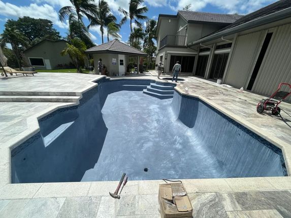 A large swimming pool is being built in the backyard of a house.