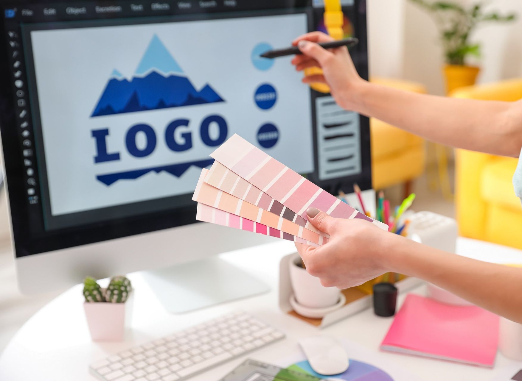 A person is holding a color palette in front of a computer screen.