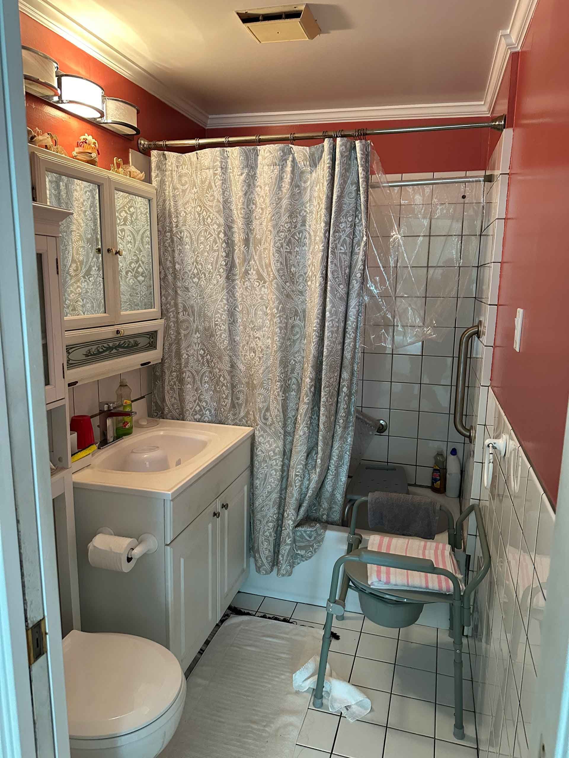 A bathroom with a toilet , sink , shower and chair.