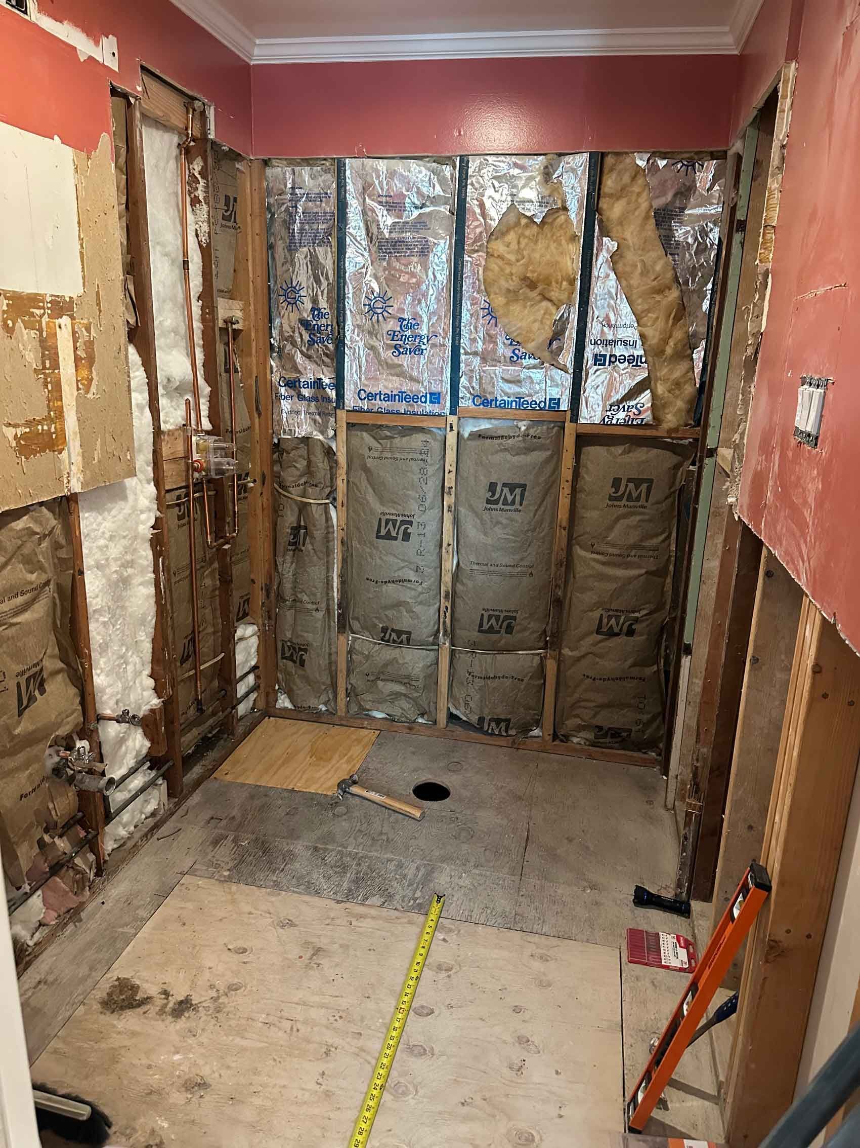A bathroom under construction with a tape measure on the floor.