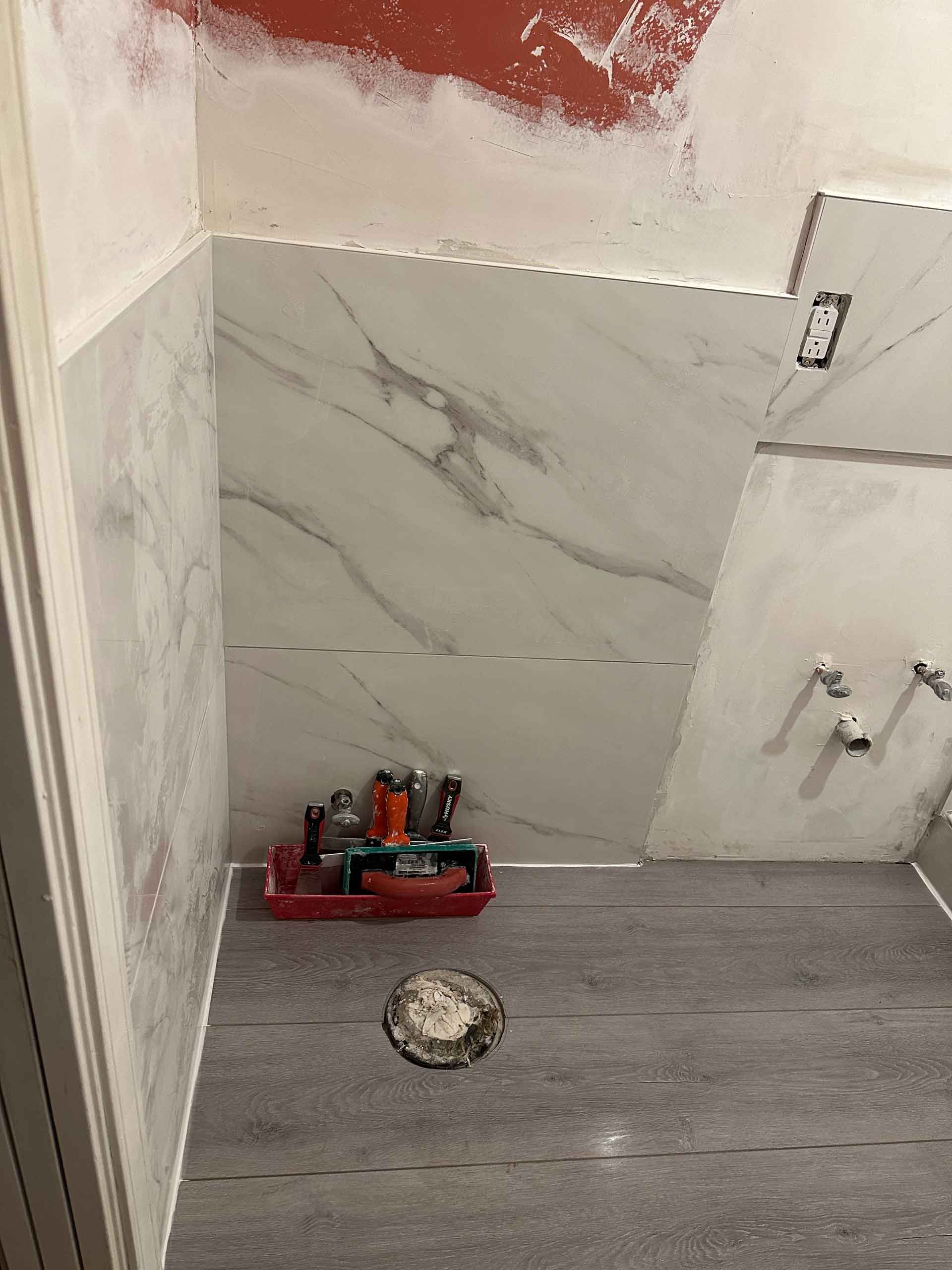A bathroom under construction with a drain in the floor.