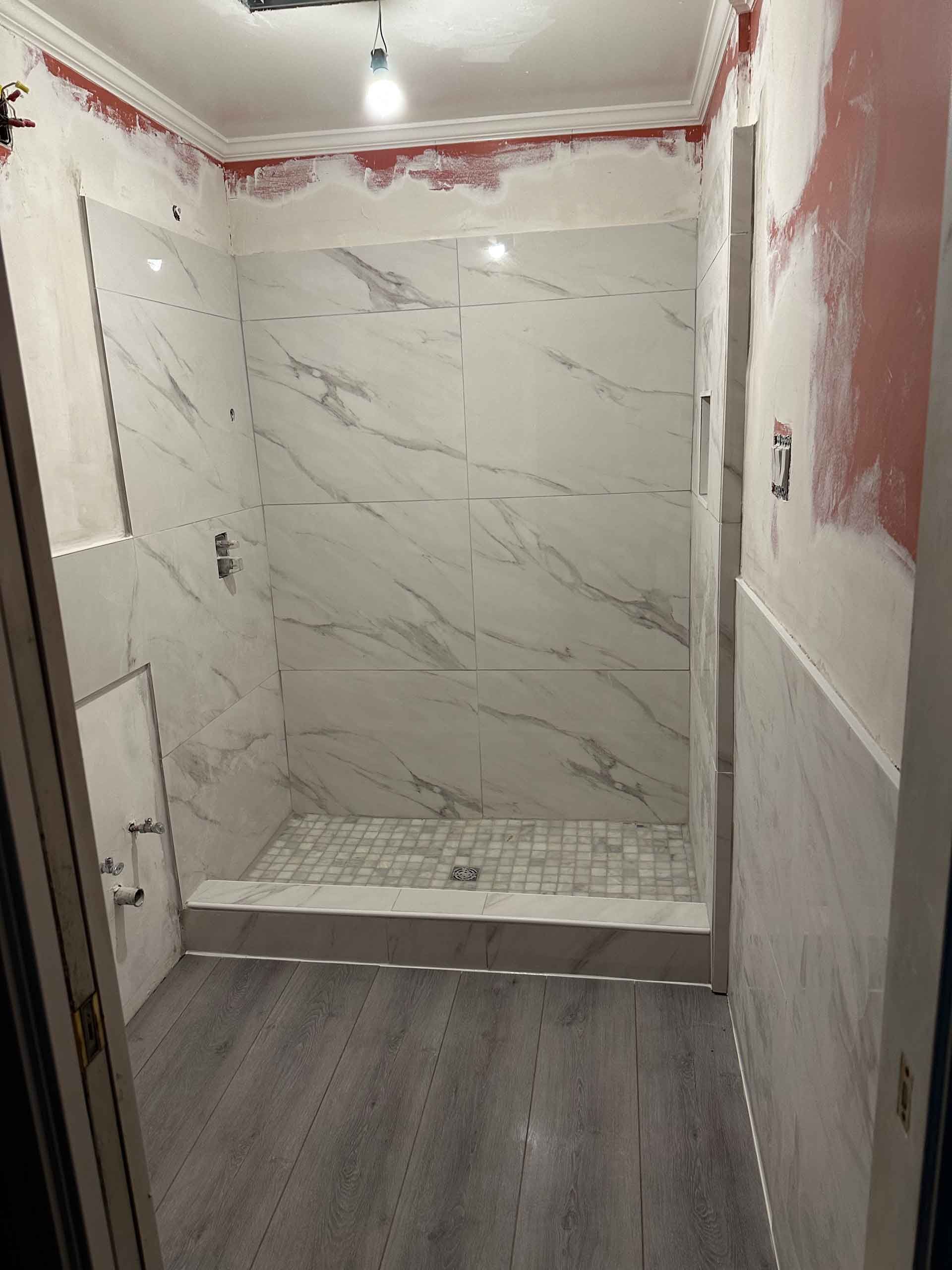 A bathroom with marble tiles and a walk in shower.